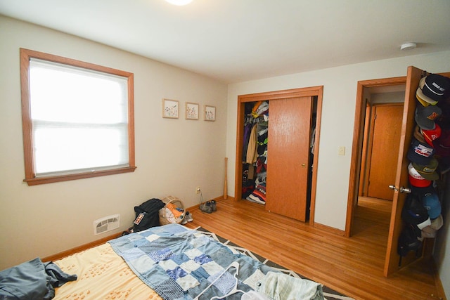 bedroom featuring a closet, visible vents, baseboards, and wood finished floors