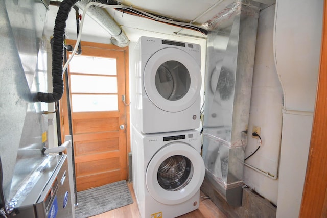 clothes washing area with laundry area, light wood-style floors, and stacked washing maching and dryer