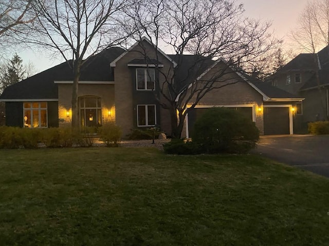 traditional-style house with aphalt driveway, a garage, and a front yard