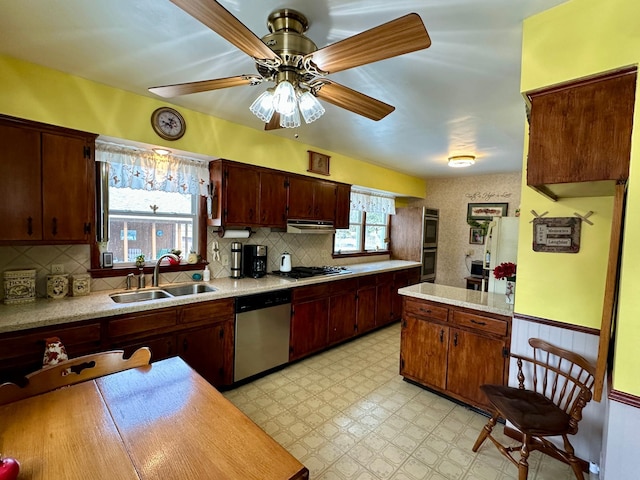 kitchen with under cabinet range hood, light floors, light countertops, appliances with stainless steel finishes, and a sink