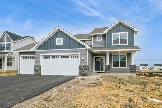 craftsman inspired home featuring aphalt driveway, an attached garage, board and batten siding, and roof with shingles