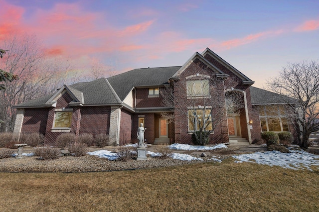 view of front of property featuring brick siding and a lawn