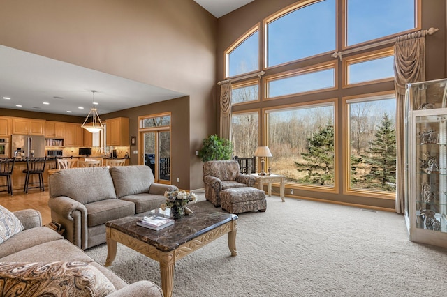 living area featuring light carpet, recessed lighting, and a high ceiling