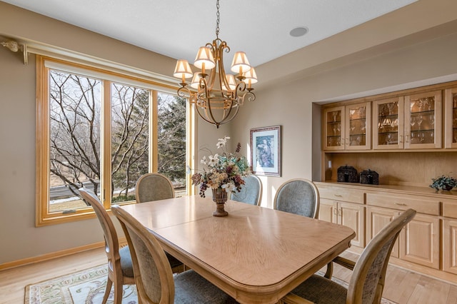 dining space with baseboards, a notable chandelier, a healthy amount of sunlight, and light wood-style flooring