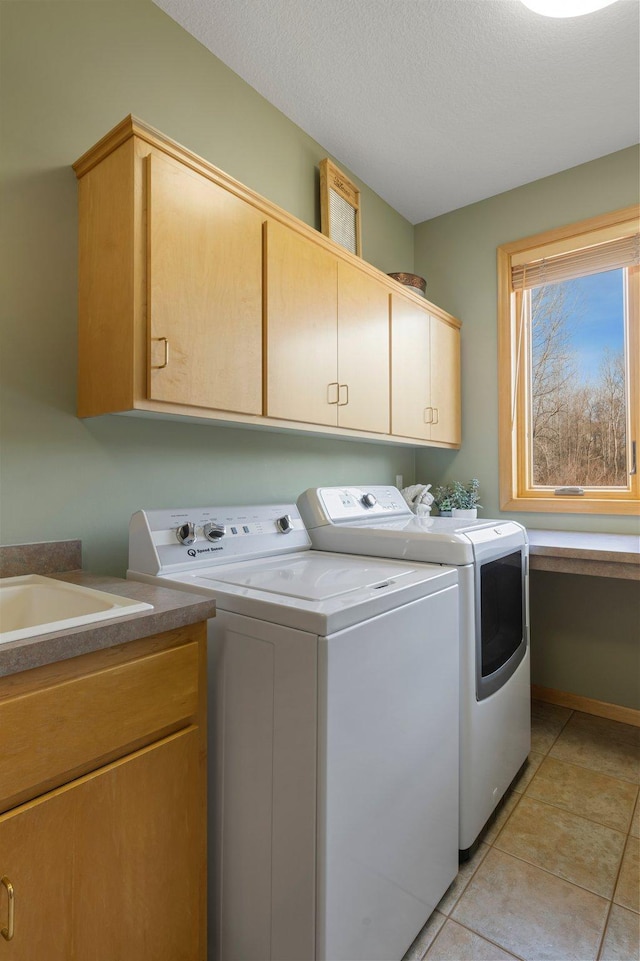 laundry area with washer and clothes dryer, light tile patterned floors, cabinet space, and a textured ceiling