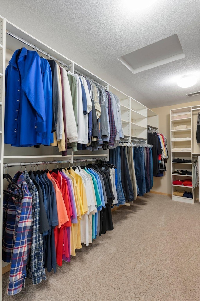 walk in closet with attic access, carpet flooring, and visible vents