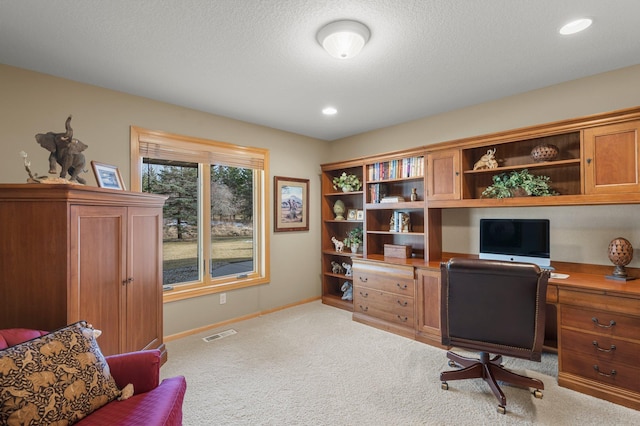 carpeted office space featuring visible vents, baseboards, built in desk, recessed lighting, and a textured ceiling