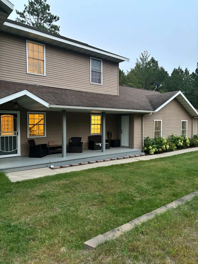 rear view of property with a lawn, a shingled roof, and a patio