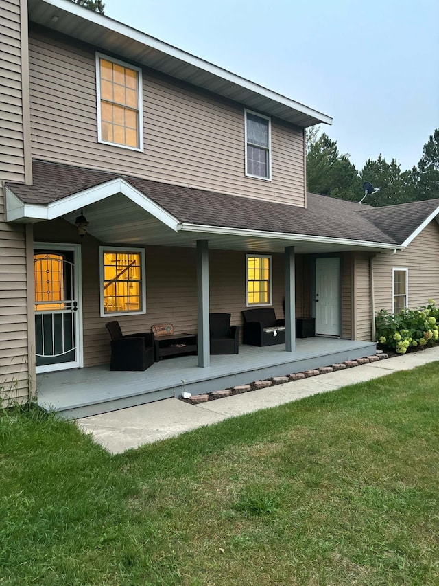 rear view of house featuring a yard and roof with shingles