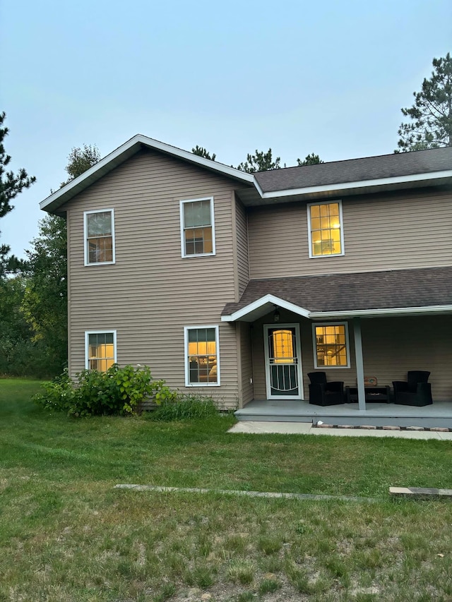 view of front of home with a patio, roof with shingles, and a front lawn