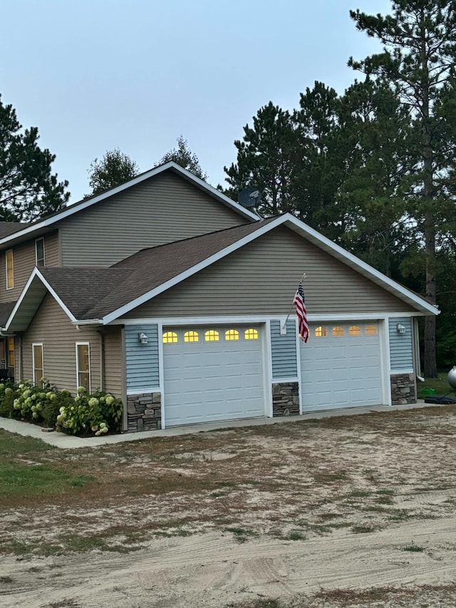 view of front facade featuring stone siding, driveway, and a garage