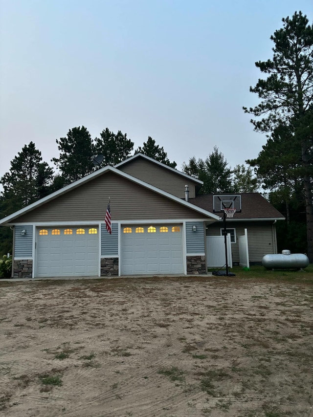 view of front of house with stone siding, driveway, and a garage