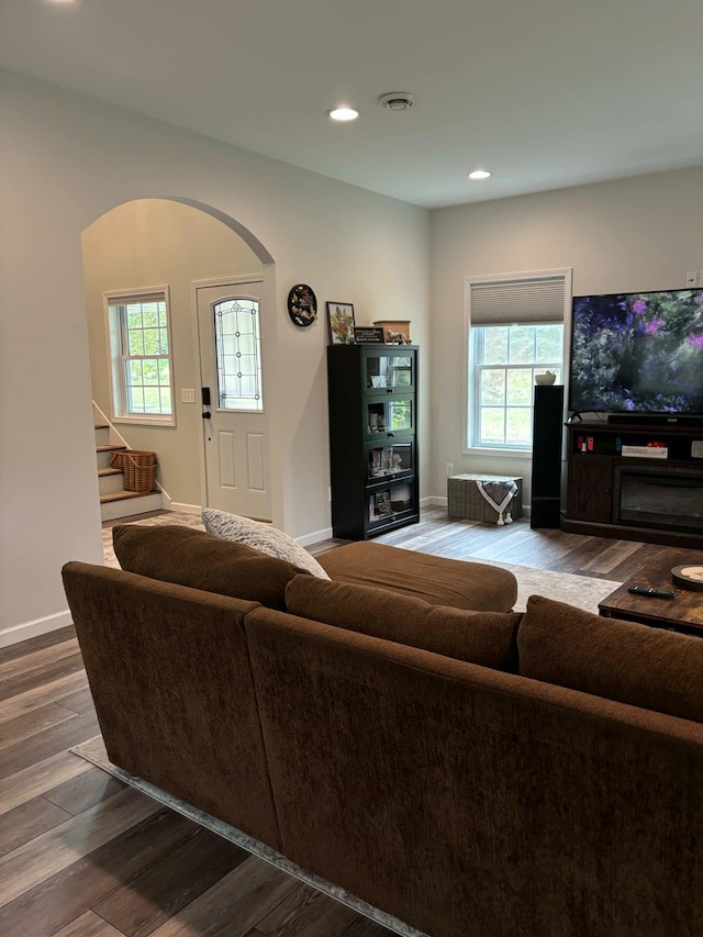 living area featuring wood finished floors, recessed lighting, arched walkways, baseboards, and stairs