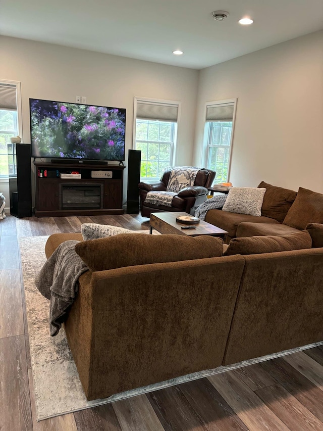 living area with a glass covered fireplace, recessed lighting, wood finished floors, and visible vents