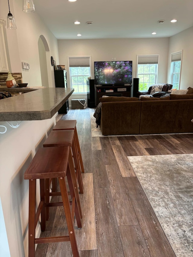 living area featuring dark wood finished floors, recessed lighting, and arched walkways