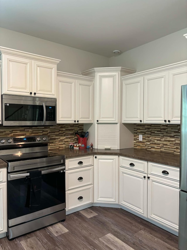 kitchen with decorative backsplash, dark wood-type flooring, dark countertops, and appliances with stainless steel finishes