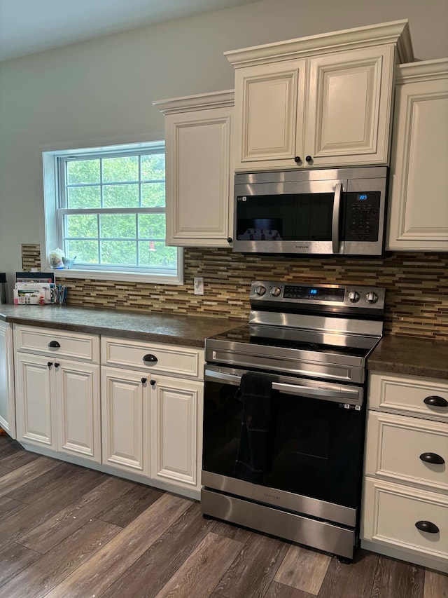 kitchen with tasteful backsplash, dark wood finished floors, stainless steel appliances, and dark countertops