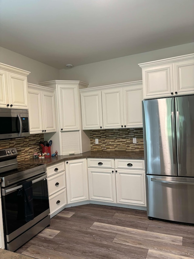 kitchen with decorative backsplash, dark countertops, appliances with stainless steel finishes, and dark wood-style floors