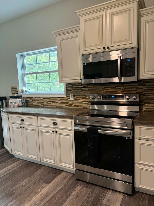 kitchen featuring dark countertops, tasteful backsplash, appliances with stainless steel finishes, and dark wood finished floors