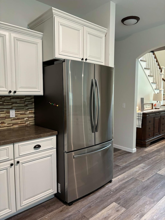 kitchen with wood finished floors, freestanding refrigerator, white cabinets, dark countertops, and tasteful backsplash