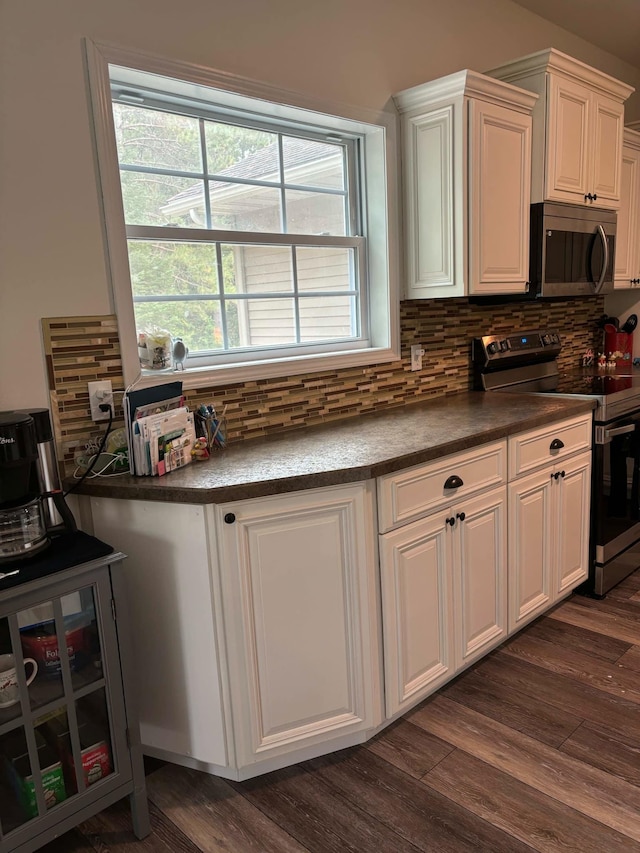 kitchen featuring stainless steel appliances, decorative backsplash, dark wood-type flooring, white cabinets, and dark countertops