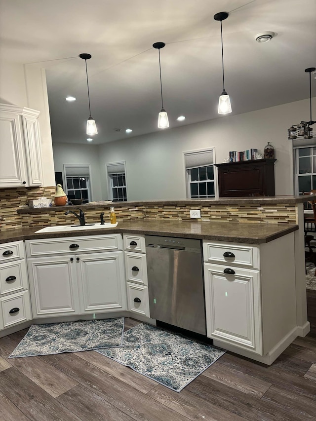 kitchen with a sink, dark countertops, dishwasher, and dark wood-style floors