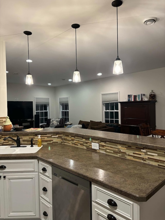 kitchen featuring visible vents, a sink, stainless steel dishwasher, dark countertops, and open floor plan