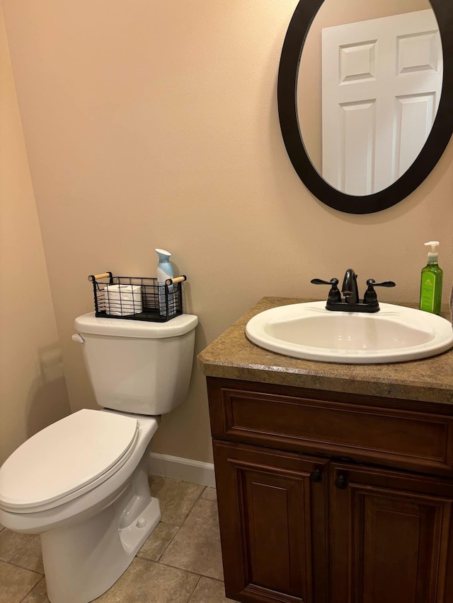 half bath with tile patterned flooring, toilet, vanity, and baseboards