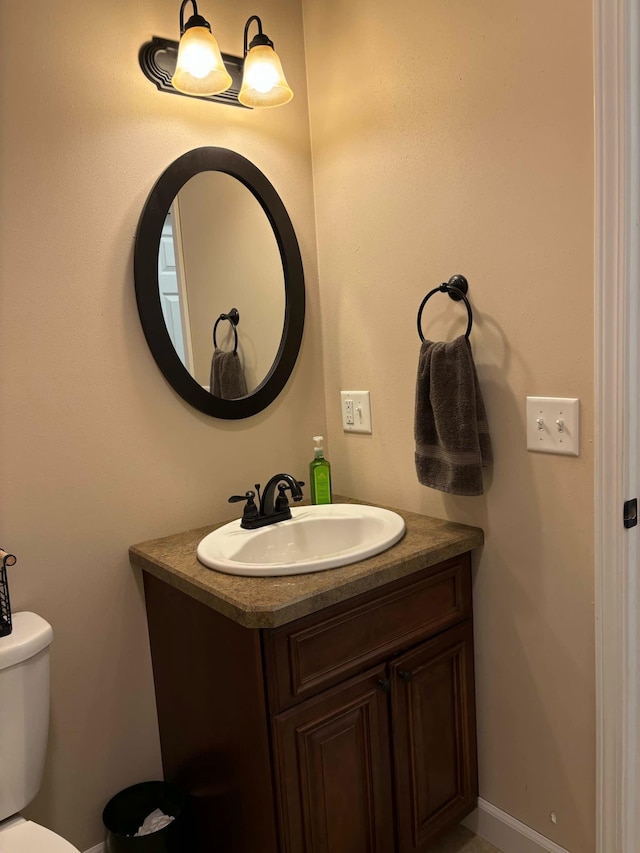 half bathroom with vanity, toilet, and baseboards