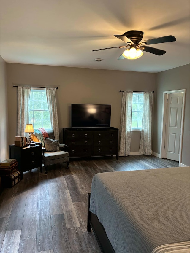 bedroom featuring ceiling fan, baseboards, multiple windows, and dark wood-style floors