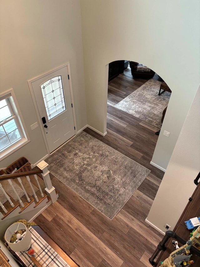 entryway with a high ceiling, baseboards, and wood finished floors