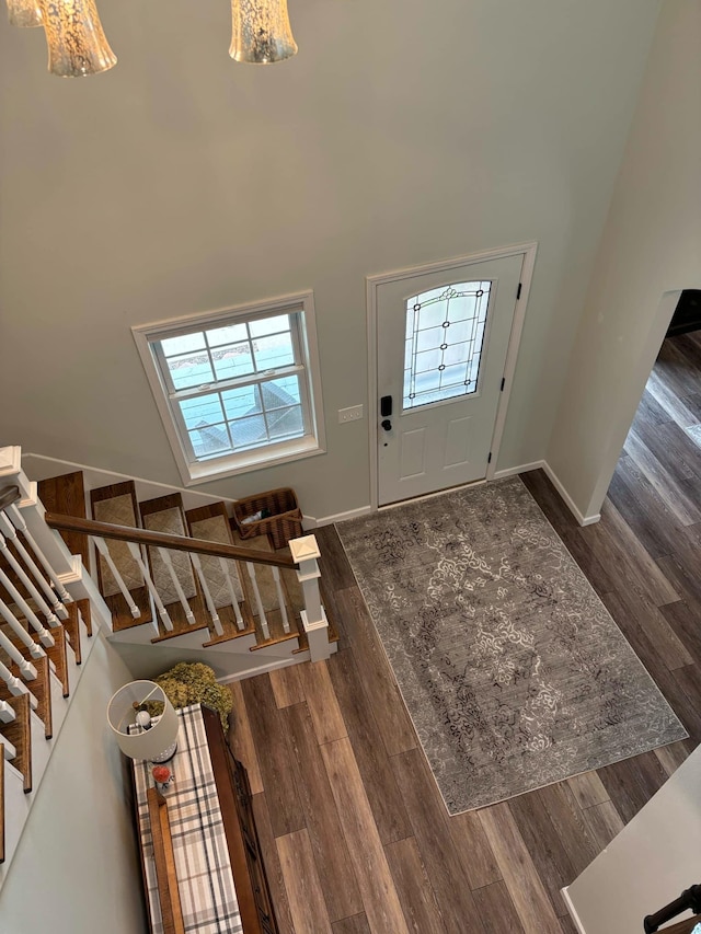 entrance foyer with stairway, baseboards, a high ceiling, and wood finished floors