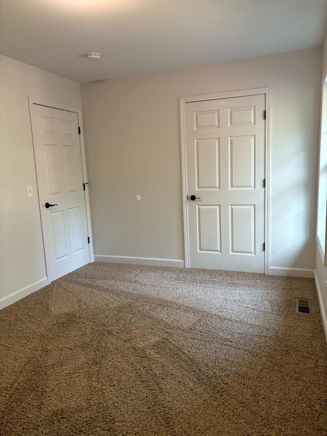 unfurnished bedroom featuring carpet, visible vents, and baseboards