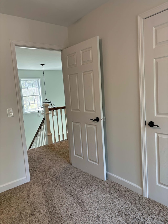 corridor with an upstairs landing, carpet, and baseboards