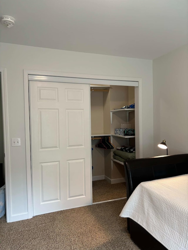 carpeted bedroom with a closet and baseboards