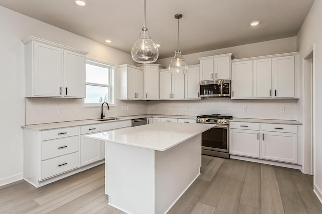 kitchen with white cabinets, appliances with stainless steel finishes, light countertops, and a sink