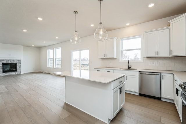 kitchen featuring a sink, stainless steel appliances, light countertops, backsplash, and a center island