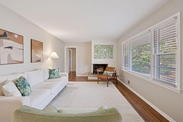 living area with visible vents, baseboards, dark wood-style floors, and a fireplace