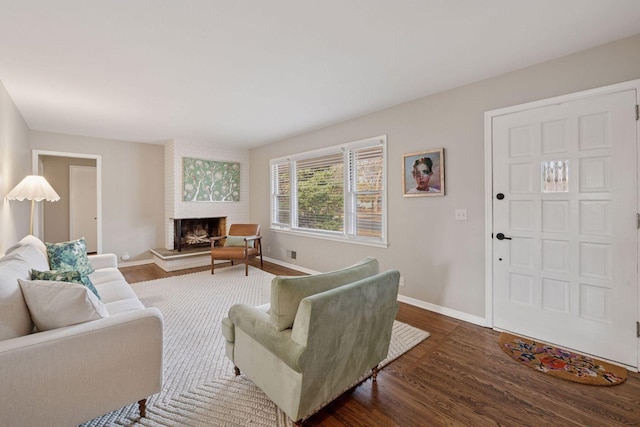 living area with baseboards, a fireplace, and dark wood-style flooring