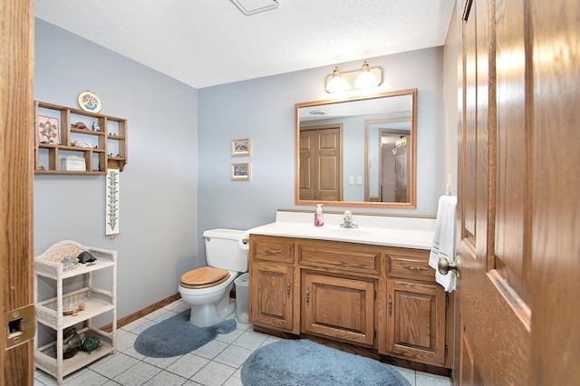 bathroom with vanity, baseboards, a textured ceiling, tile patterned floors, and toilet