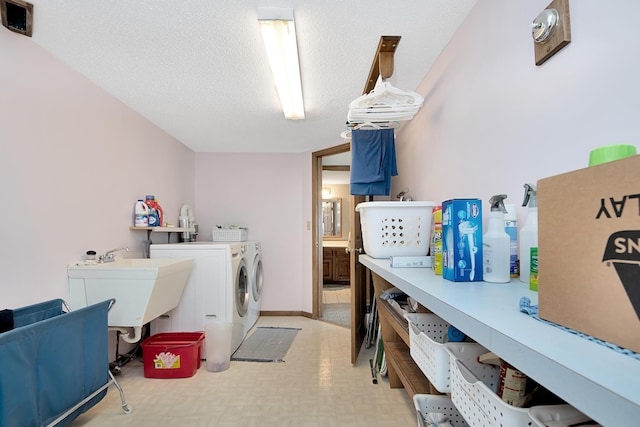 laundry area with light floors, laundry area, a sink, a textured ceiling, and washer and clothes dryer