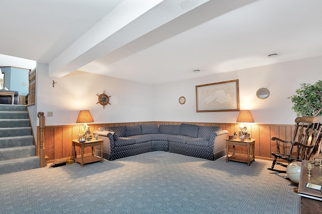 carpeted living room with stairs, wooden walls, and wainscoting