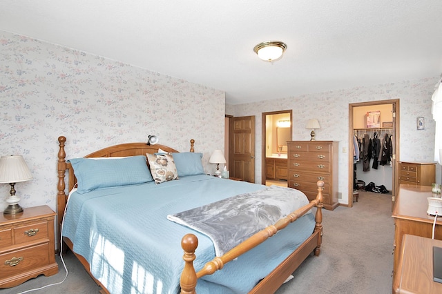 bedroom with light carpet, wallpapered walls, and a walk in closet