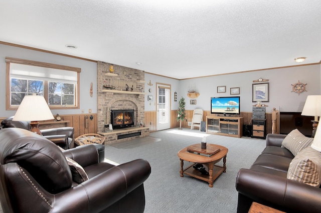 carpeted living area with a wealth of natural light, a textured ceiling, a fireplace, and crown molding