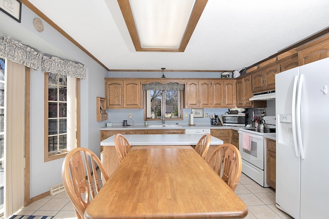 kitchen featuring under cabinet range hood, light tile patterned floors, white appliances, and light countertops