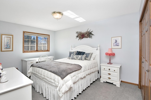 bedroom featuring a closet, light colored carpet, and baseboards