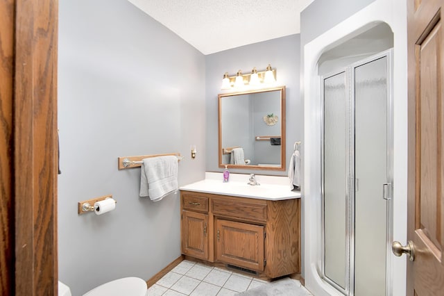 bathroom with toilet, vanity, a stall shower, tile patterned floors, and a textured ceiling