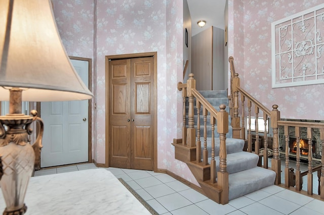 staircase featuring tile patterned floors, baseboards, and wallpapered walls