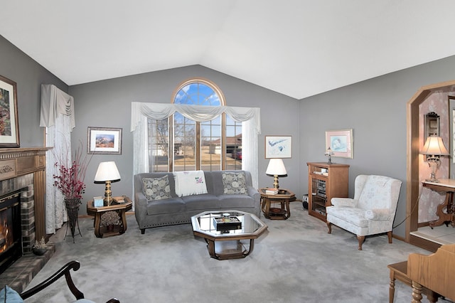 living area with vaulted ceiling, a brick fireplace, carpet, and arched walkways