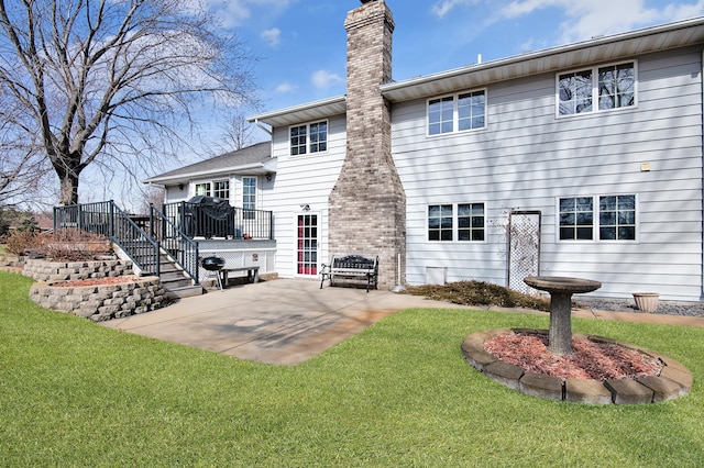 back of house featuring a patio, a wooden deck, a lawn, and a chimney